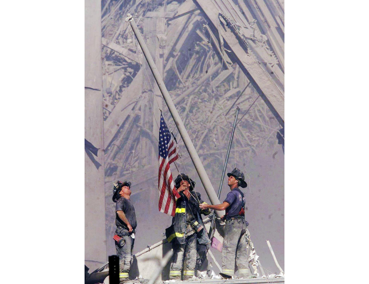 Firefighters raise a flag late in the afternoon of Sept. 11, 2001, in the wreckage of the World Trade Center towers.