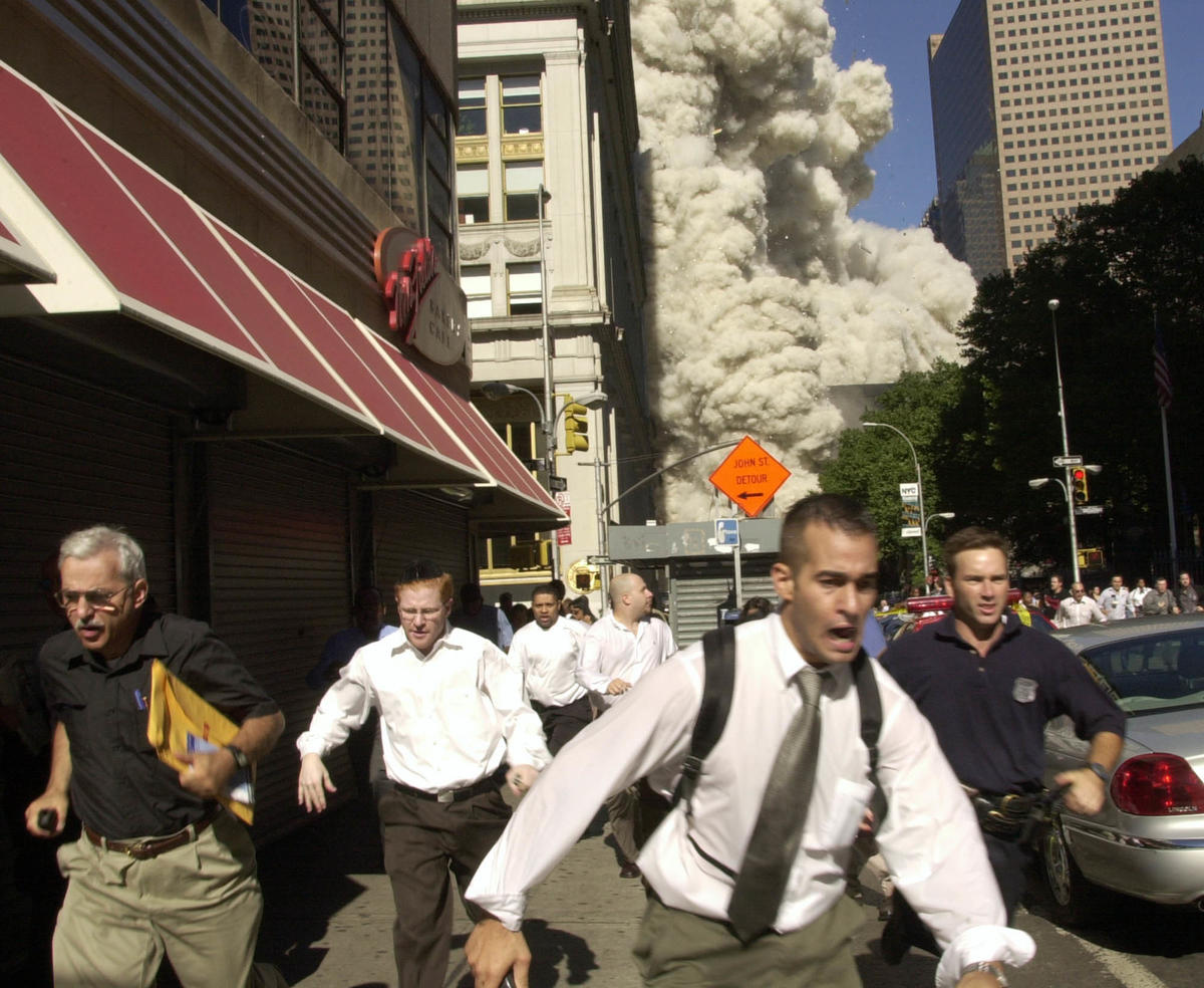 People flee as a World Trade Center tower collapses behind them. 