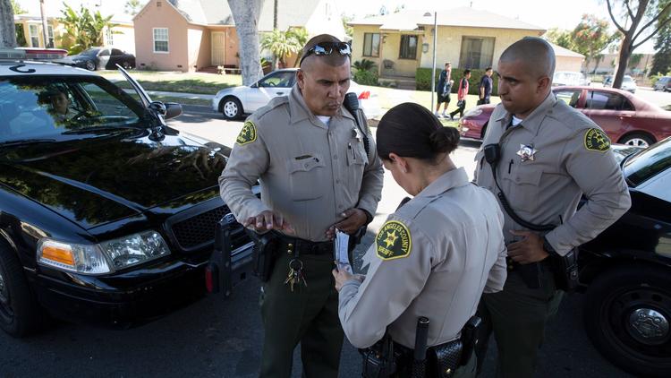 Sheriff's deputy Marino Gonzalez, left, talks with deputies while investigating a disturbance in May
