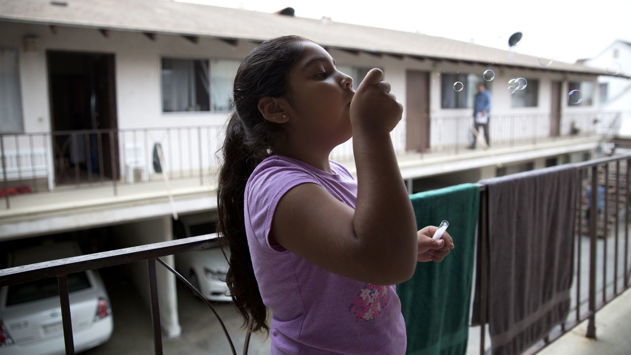 As her family packs the car to move, Luz Madrigal, 6, blows bubbles on the balcony of her apartment in Gardena.
