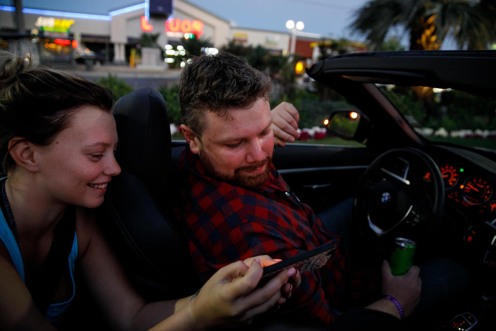 Kamryn Trubey shows Brian MacKinnon photos of his childhood friend Adrian Murfitt taken with Trubey when they met at the concert before the mass shooting changed their lives forever. — Photograph: Marcus Yam/Los Angeles Times.
