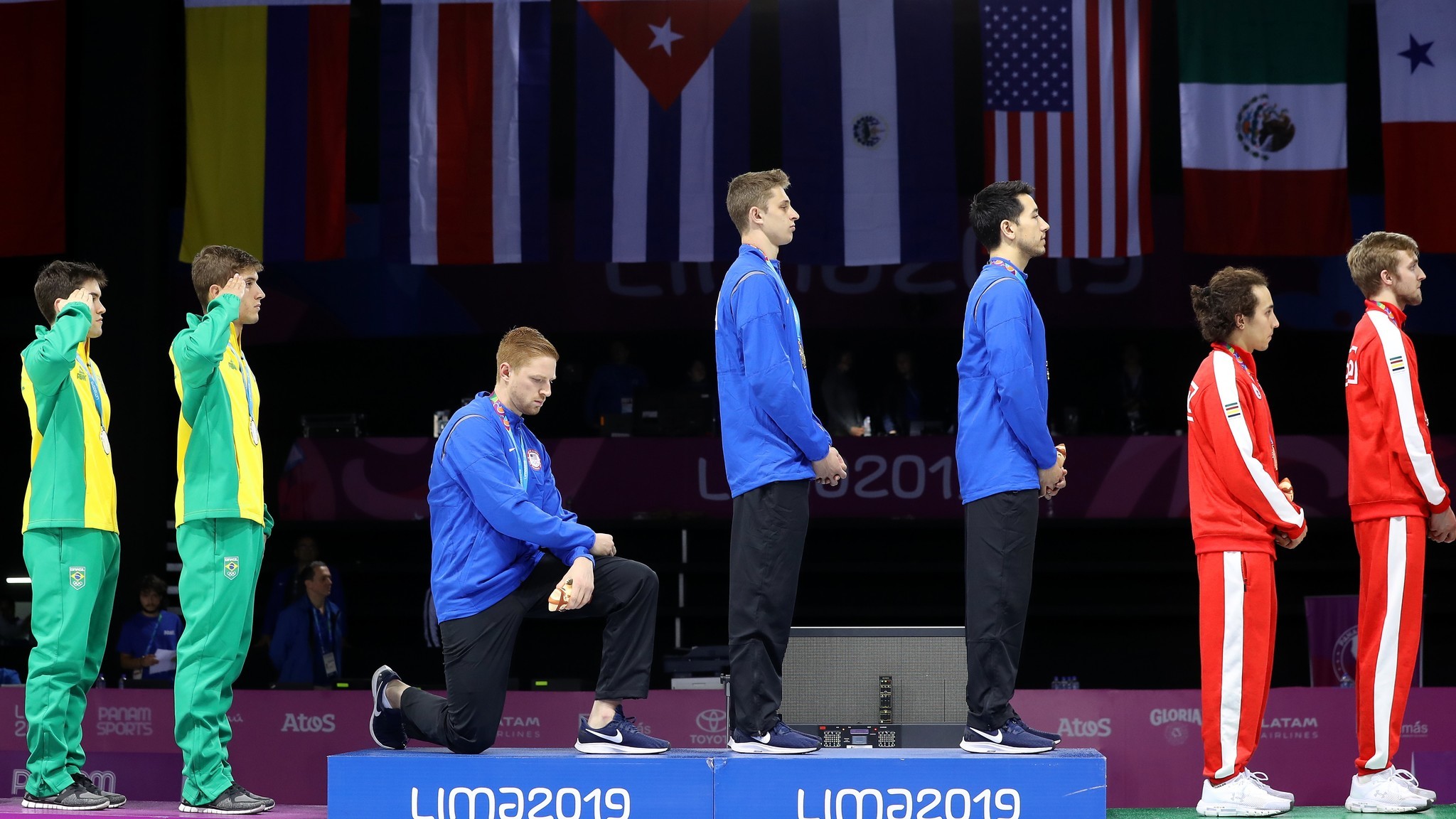 Fencer and hammer thrower kneel, raise fist for anthem at Pan Am Games