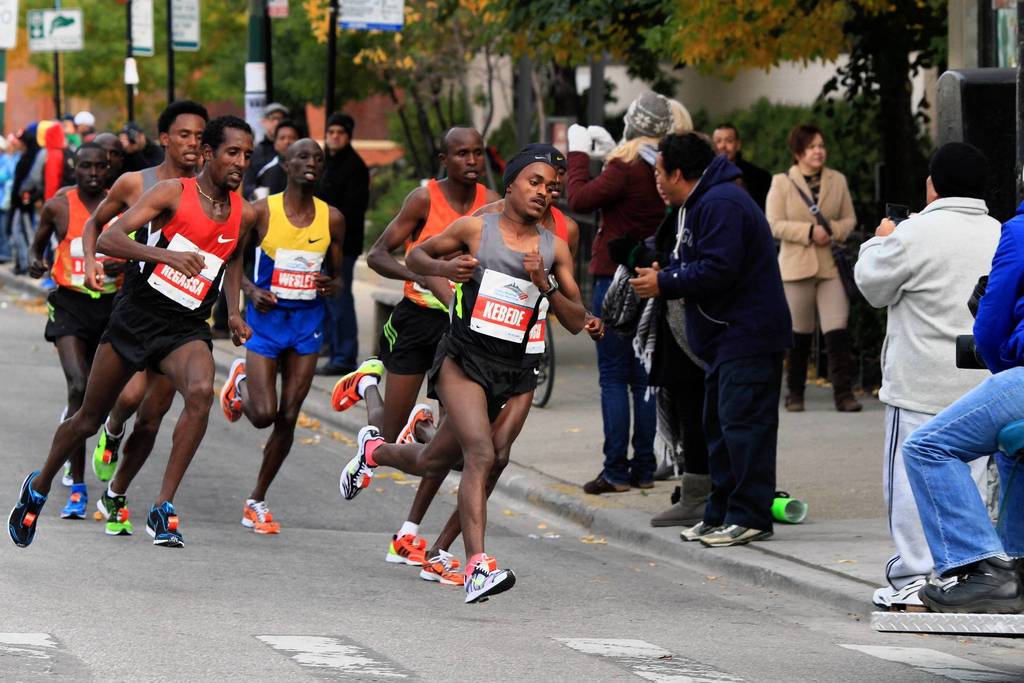 Tsegaye Kebede, of Ethiopia, center takes the lead while Tilahun Regassa, of Ethiopia, left, follows in Chicago's Pilsen neighborhood during the Bank of America Chicago Marathon.