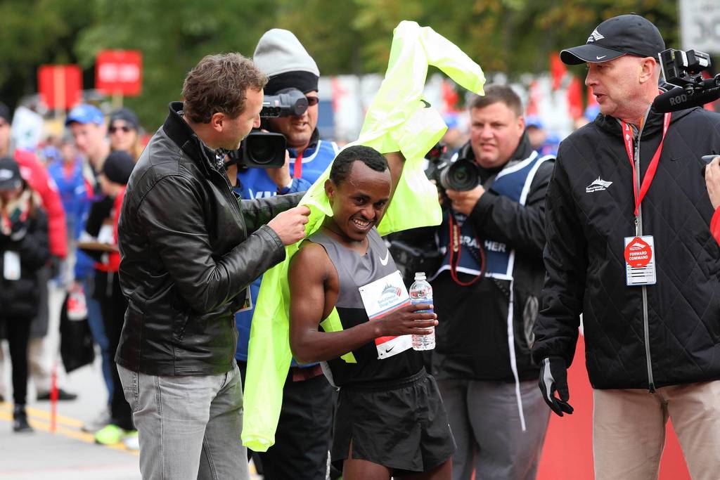 Tsegaye Kebede gets help with his jacket after becoming the first Ethiopian to win the Bank of America Chicago Marathon, breaking the year-old course record by nearly a minute.
