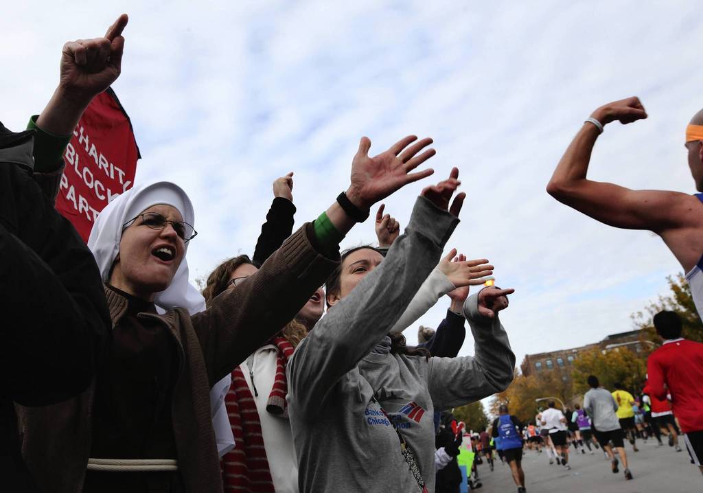 Sister Alicia Torres, left, of Team Our Lady of Angels in Chicago, is joined by Courtney Bonty, of Champaign, in cheering runners as they head down Adams at Loomis.