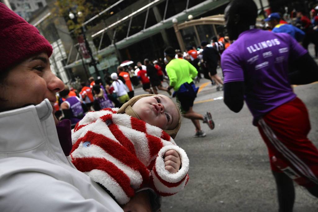 Pamela Huber, of Boston, with her one-year old son Trevor, 1, watches for her husband to run down State Street during the Bank of America Chicago Marathon.