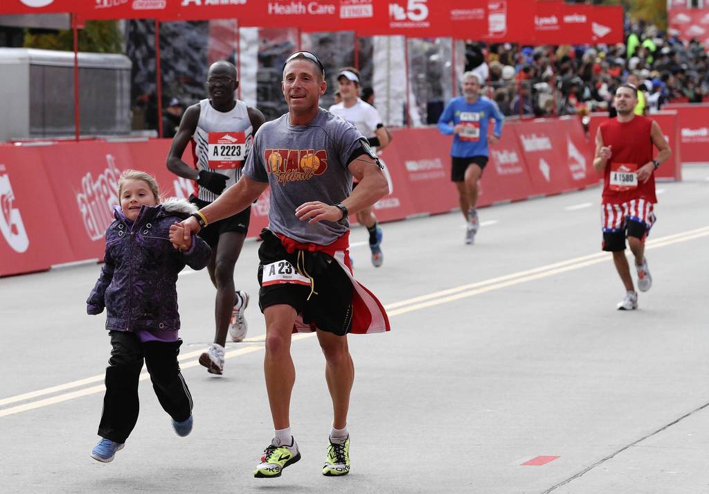 A runner crosses the finish line on Columbus Drive with a young helper at the Bank of America Chicago Marathon.