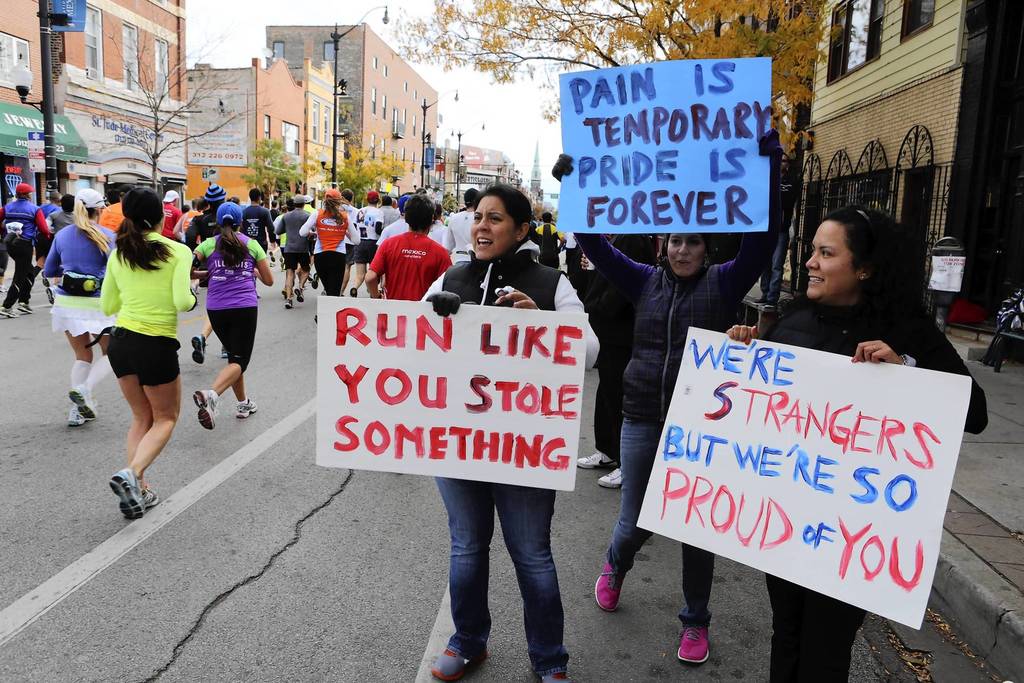 Sandra, Leslie and Consuelo Rodriguez,a trio of sisters, encourage Chicago Marathon runners with their creative signage at mile 19 near the intersection of Ashland Avenue and 18th Street in the Pilsen neighborhood of Chicago.