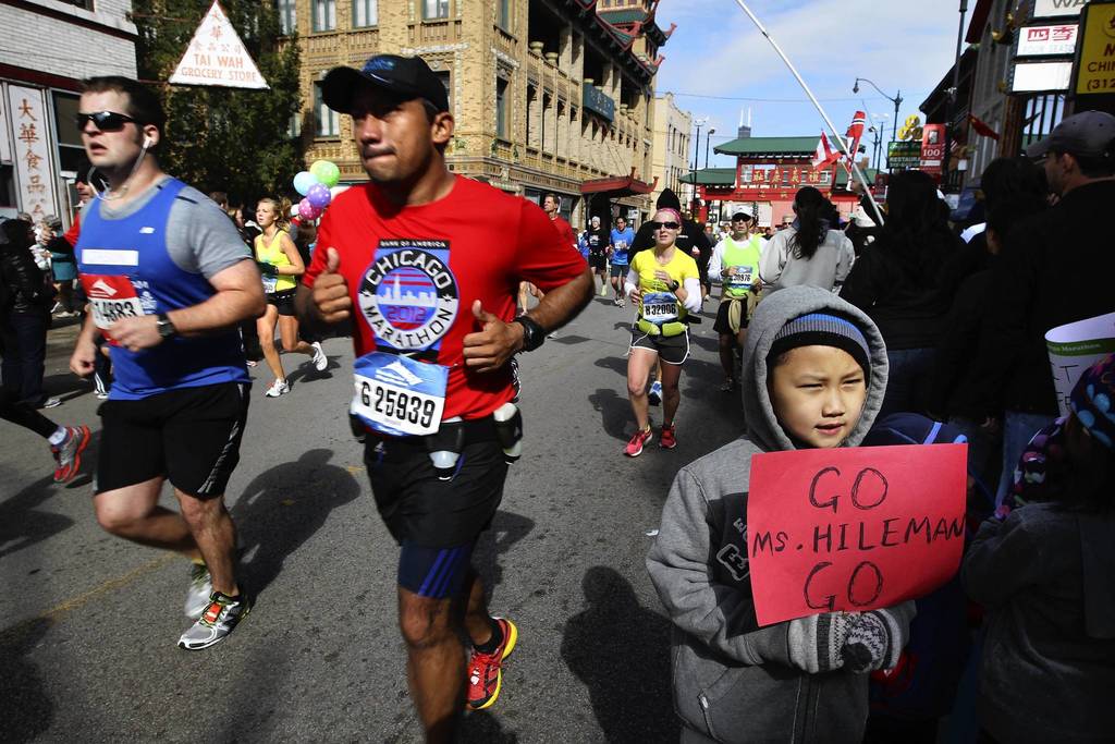 Brendon Xu, 8, has his photo taken by his mother as he waits for his teacher assistant at Skinner school to pass by in Chinatown during the 35th Chicago Marathon.