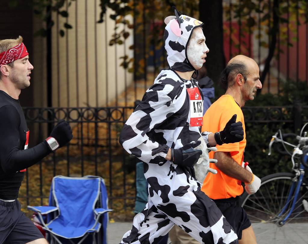 The streets of the Pilsen neighborhood are filled with runners, including one disguised as a Holstein, at mile 19 of the Bank of America Chicago Marathon.