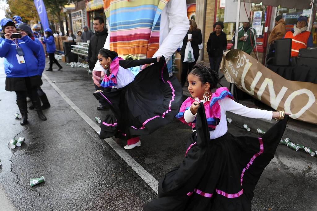 Sisters Samantha, 9, left, and Karen Dorado, 6, perform Mexican folk dances for runners making their way through the Pilsen neighborhood during the Chicago Marathon.