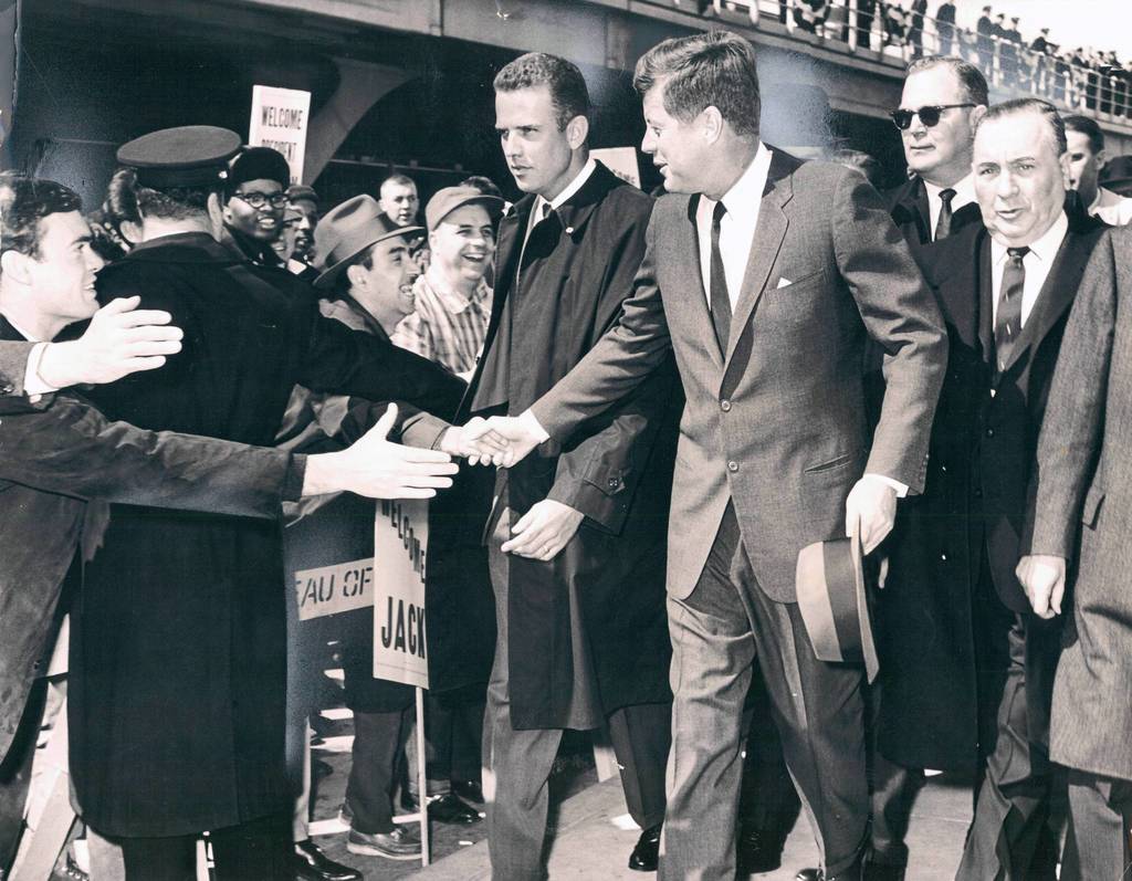 Eager hands reach toward President John F. Kennedy as he walks from the O'Hare International Airport terminal building with Mayor Daley, right, on March 23, 1963. Approximately 5,000 people gathered at the airport to catch a glimpse of the president. A secret service agent is at Kennedy's right.