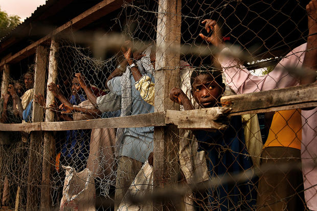 At a camp in Dadaab, people lined up to receive food are funneled through tunnels similar to cattle chutes. Through openings at various intervals, aid workers scoop wheat flour, cornmeal, dried peas, soy protein powder and salt into the refugees' gunnysacks. (Rick Loomis / Los Angeles Times)