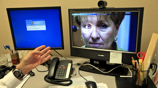 From an office in Ridgecrest, Dr. Ferguson communicates with Laura Saldana, clinic manager at Southern Inyo Hospital clinic in Lone Pine, who demonstrates some uses of the technology. (Francine Orr / Los Angeles Times)