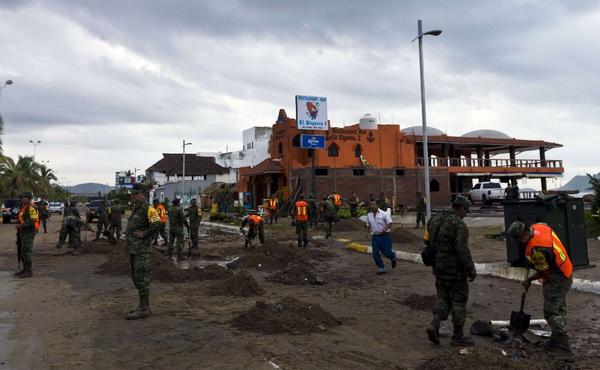 Soldiers and rescue workers begin to clean up a street in Manzanillo the morning after Hurricane Patricia made landfall. The storm brought far less damage than was initially feared. (Getty Images)