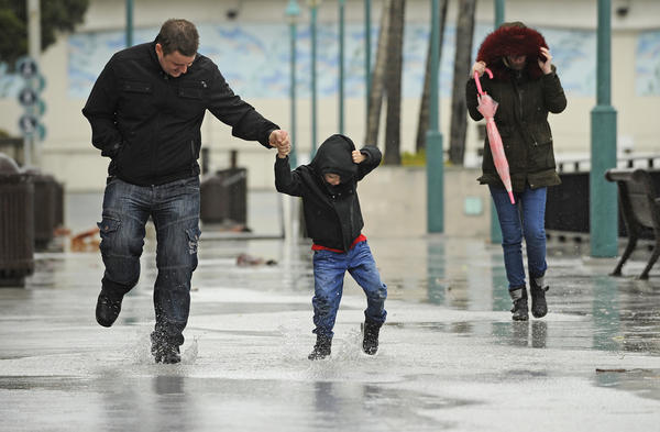 Scott Hesford-Hensler, left, plays in the rain with his son Jayden, 5, and wife, Danielle, at King Harbour in Redondo Beach. (Christina House / For The Times)