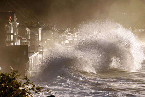 Forceful and beautiful waves crash into the sea walls of homes at Mondos Beach under the mountains of the recent Solimar fire at high tide sunrise west of Ventura on Thursday morning. (Al Seib / Los Angeles Times)