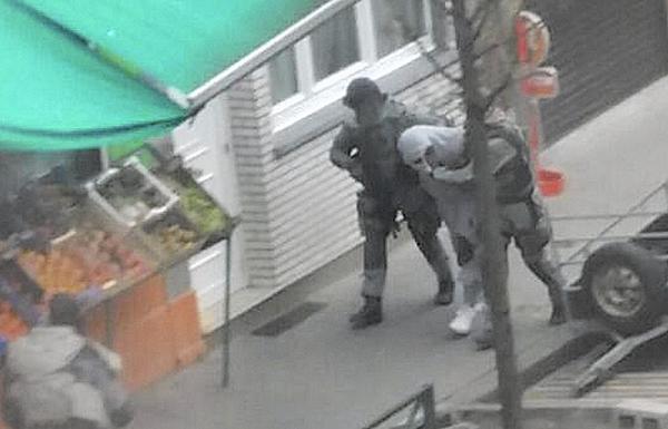 Police detain a man in Brussels' Molenbeek district on March 19 who is believed to be connected to a suspect in the Paris attacks. Residents say the district shouldn't be demonized for the actions of a few. (Zouheir Ambar / Associated Press)