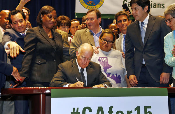 California Gov. Jerry Brown signs the minimum wage bill, raising the wage to $15 an hour by 2022. 