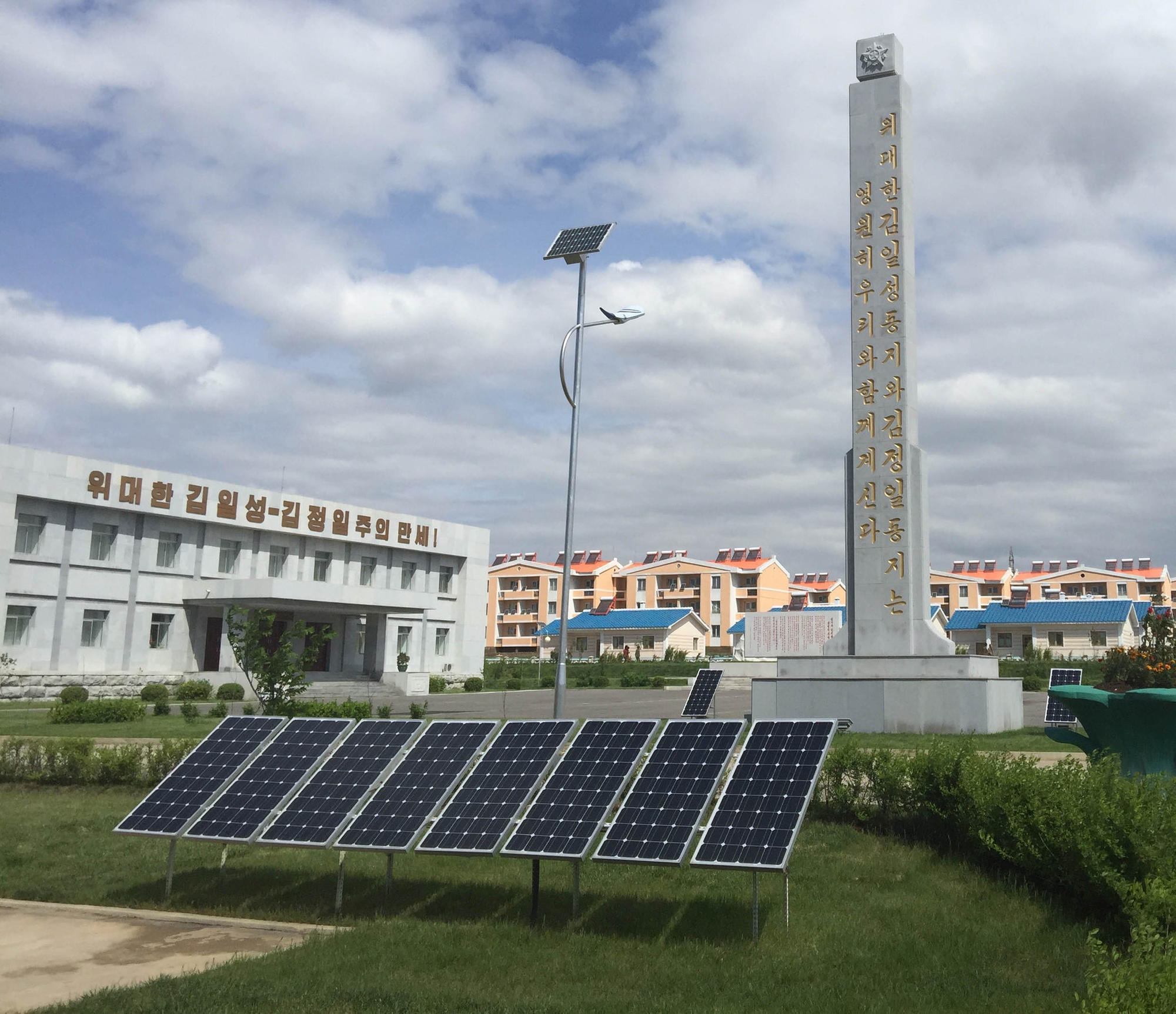 Solar panels, and a solar powered streetlight, at a farm complex on the outskirts of Pyongyang, North Korea. The worker housing in the distance has solar water heaters on the roof.