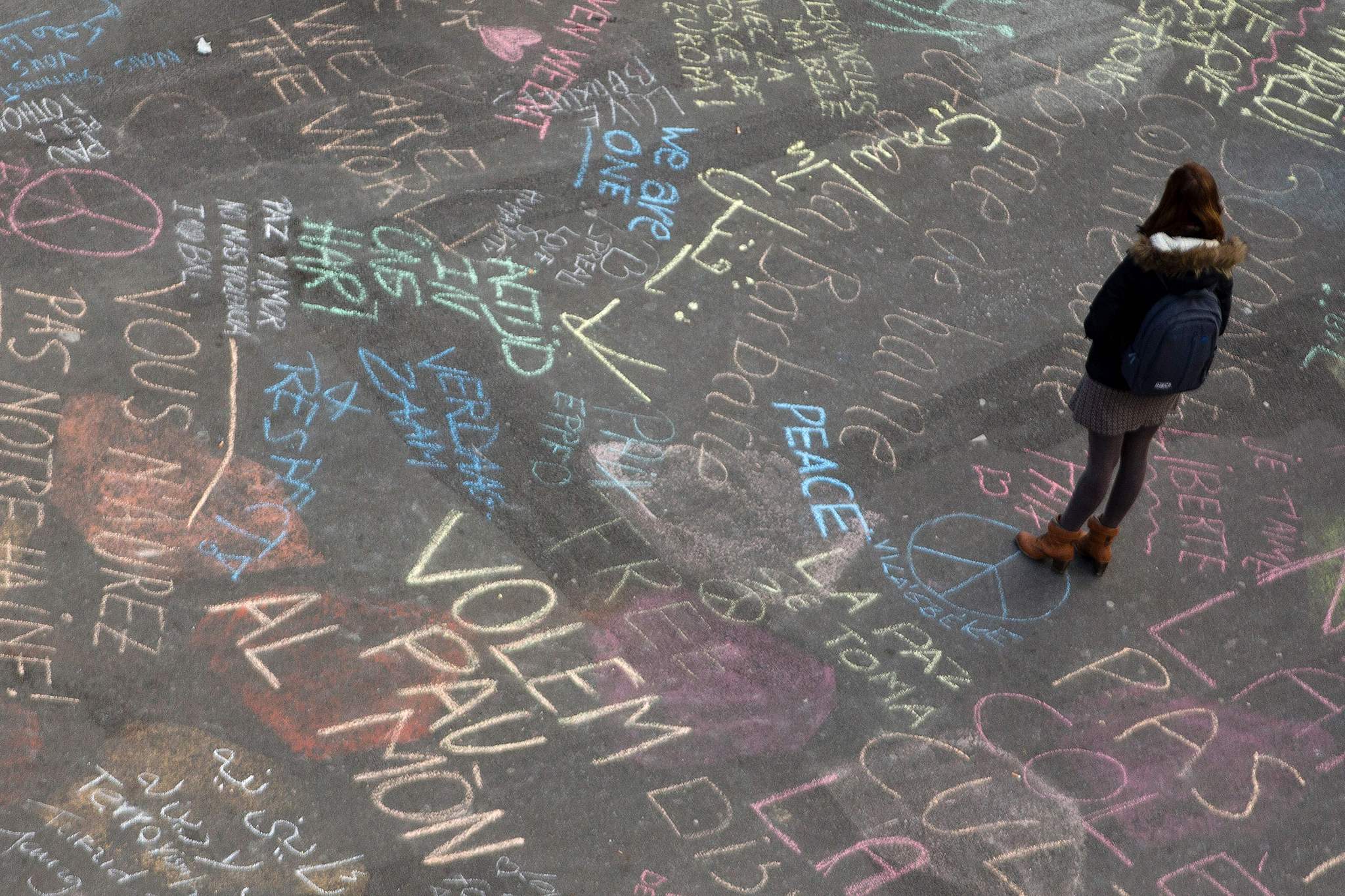 A woman reads messages written on the ground at a makeshift memorial on Place de la Bourse following attacks in Brussels.