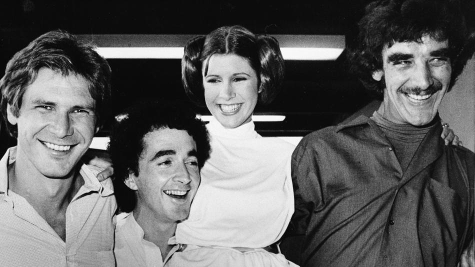 Carrie Fisher with Harrison Ford, left, Anthony Daniels and Peter Mayhew as they relax during a break from the filming of a television special presentation in Los Angeles on Oct. 5, 1978. (Associated Press)
