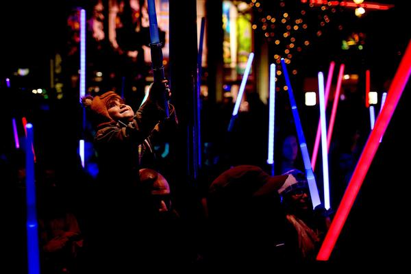Jay Cotton Jr., 4, of Whittier, sits on his father Jay Cotton's shoulders during a lightsaber vigil for "Star Wars" actress Carrie Fisher held in Downtown Disney. (Rick Loomis / Los Angeles Times)