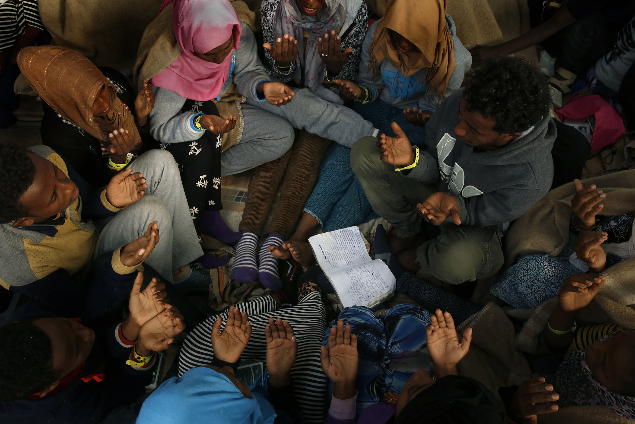 Migrants gather in a circle to sing and pray during the journey to Sicily. About 300 of the 412 rescued migrants were from Eritrea, where Christians and Muslims make up the majority of the population.