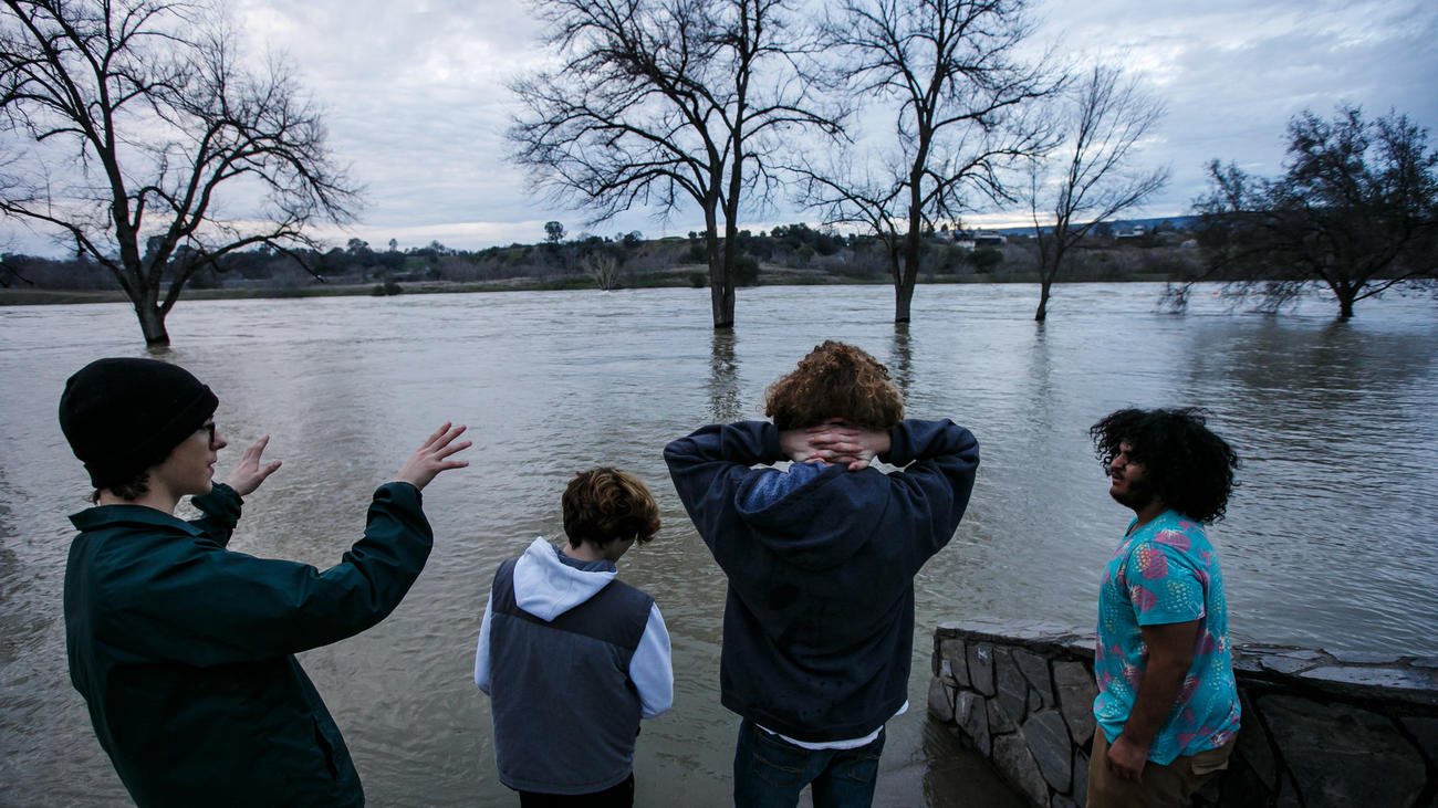 Friends Johnny Eroh, from left, Cody Balmer, Kristien Bravo and Jerel Bruhn hang out by the swollen Feather River in Oroville. (Marcus Yam / Los Angeles Times)