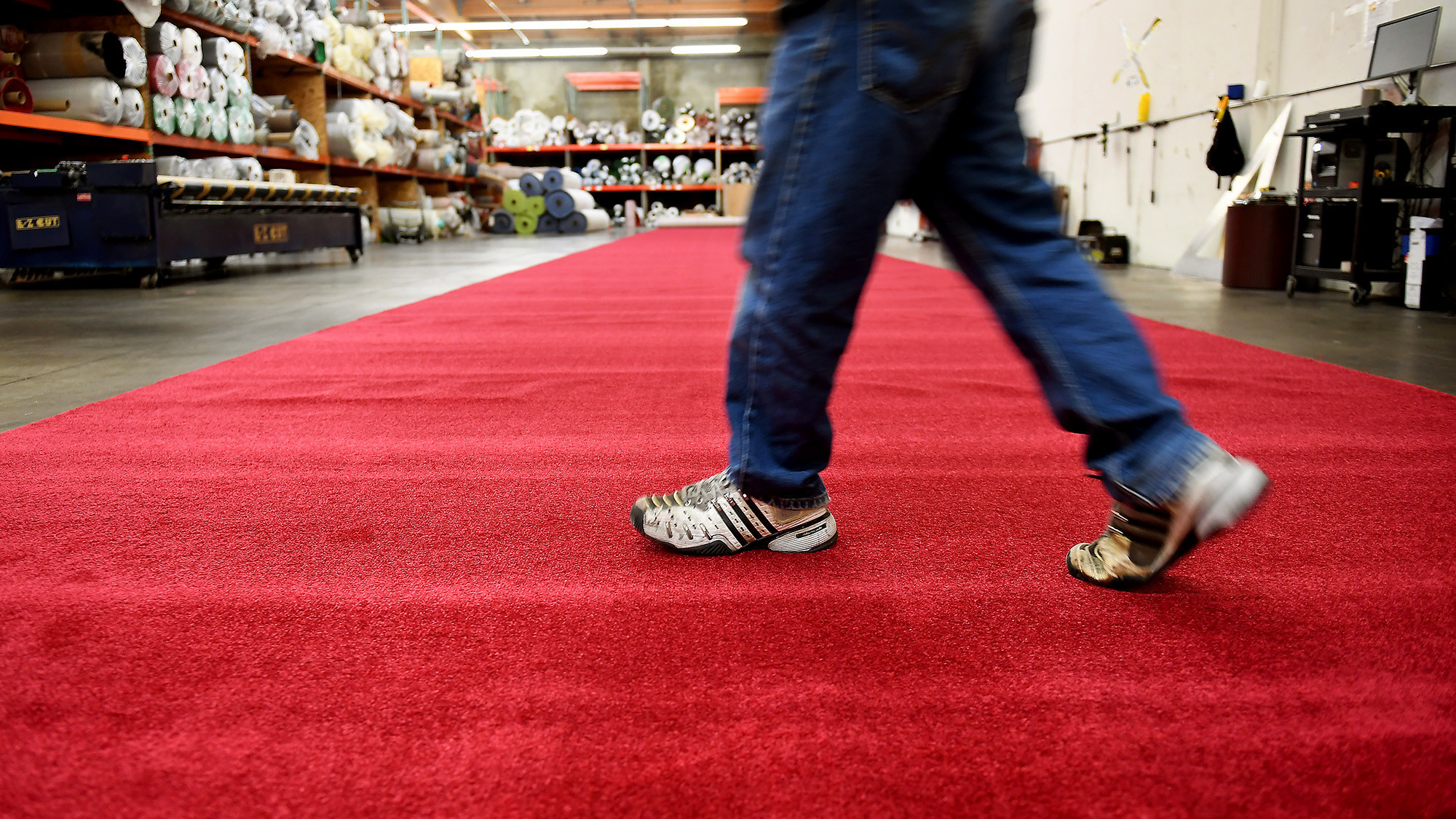 A carpet installer at Signature Systems Group walks across the red carpet in Santa Fe Springs.