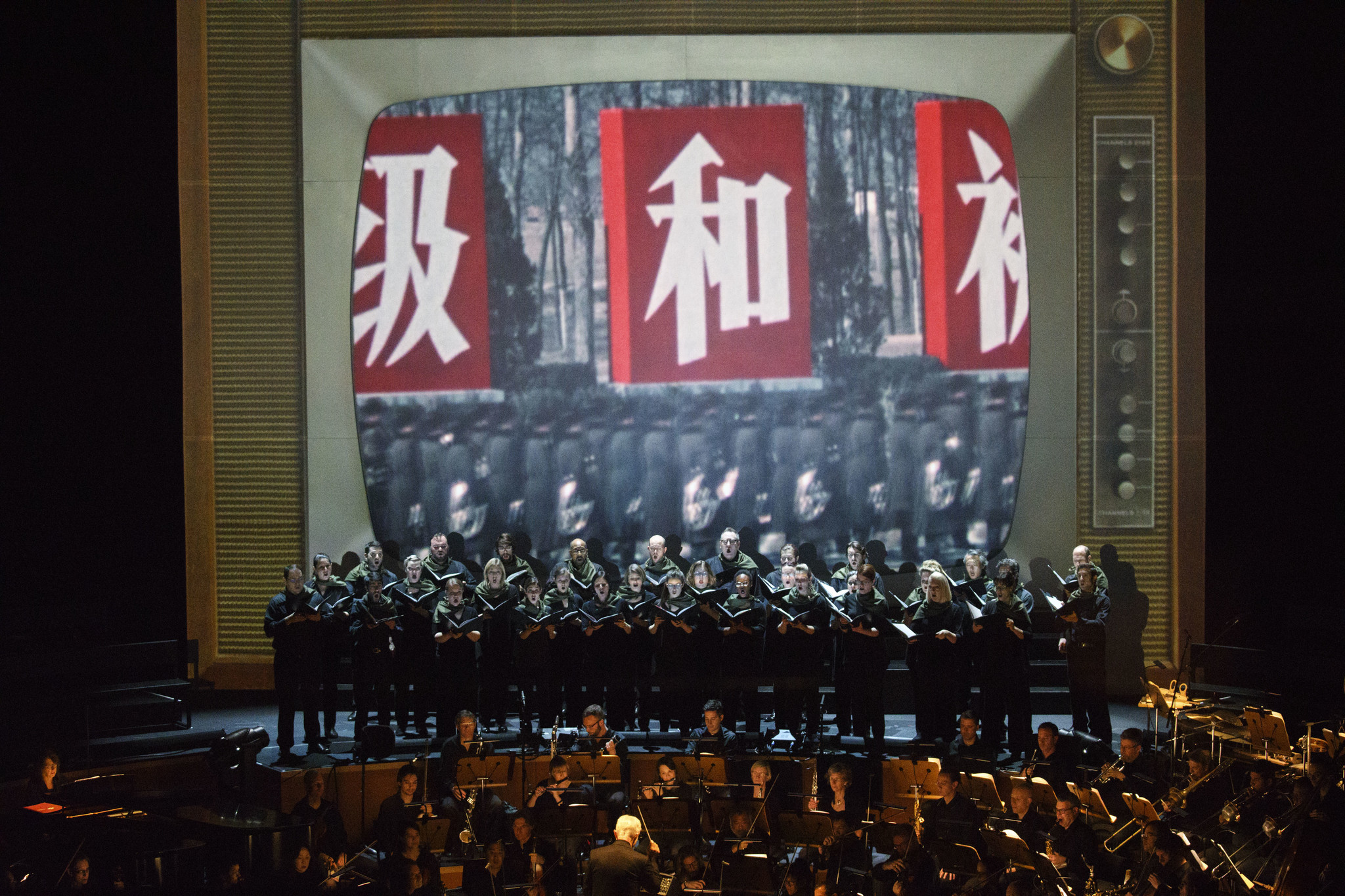 The L.A. Phil performs with the Los Angeles Master Chorale on the Disney Hall stage, backed by a projection screen made to look like a vintage TV playing historical footage during "Nixon in China."
