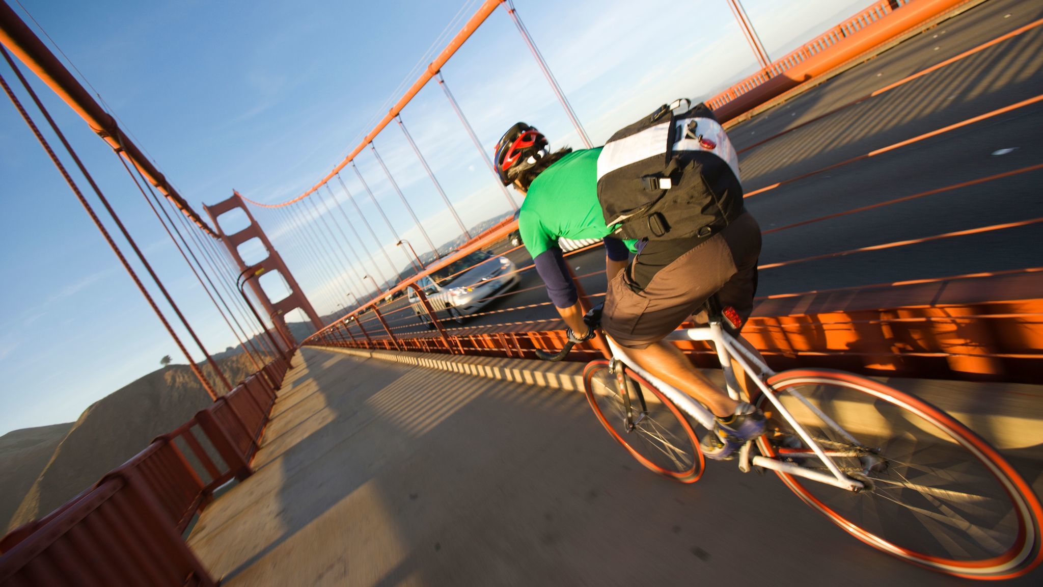 A solo cyclist crossing the Golden Gate Bridge at sunset on the commute home to the Marin near San Francisco, California.