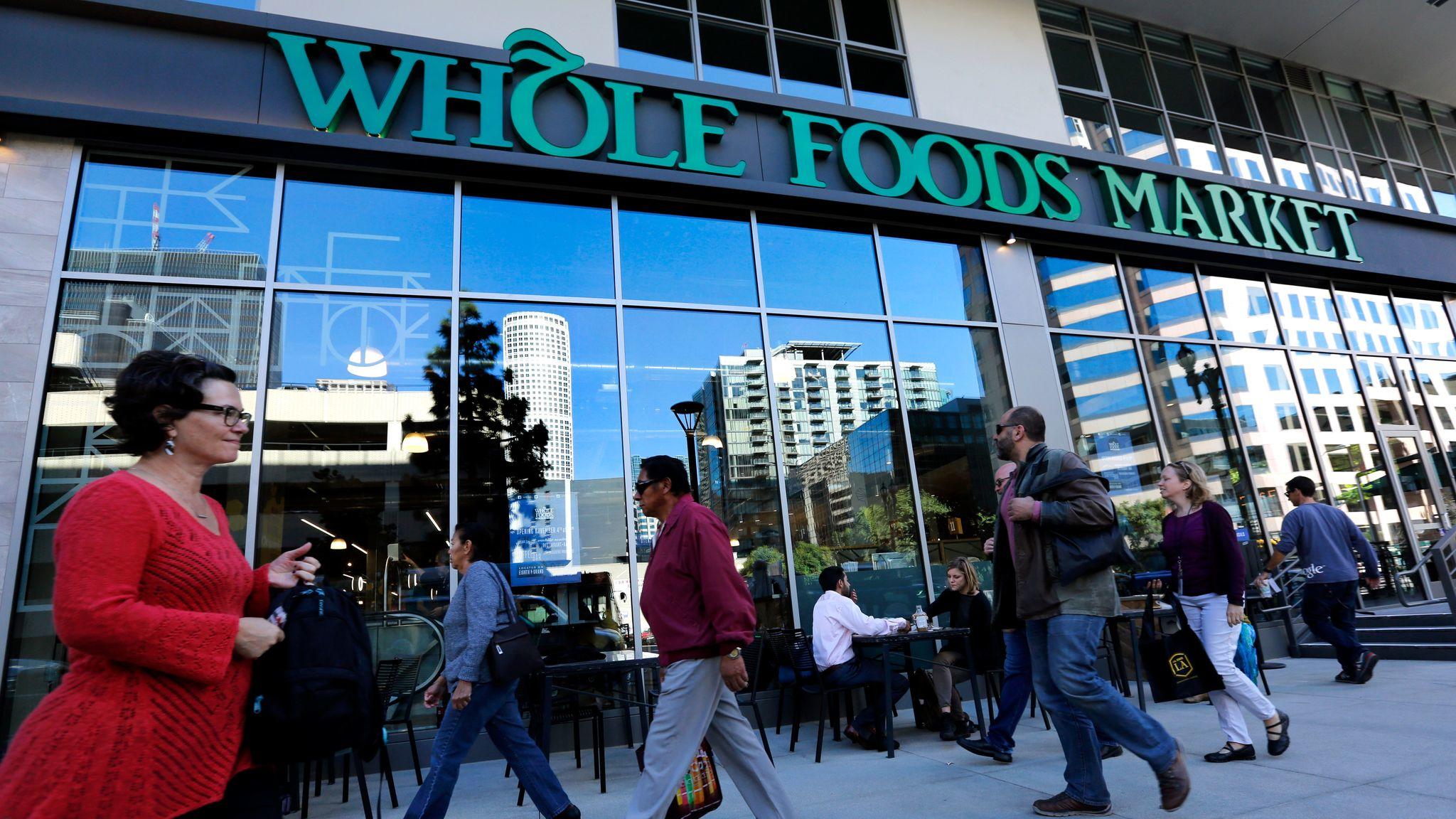 Pedestrians make their way past a Whole Foods Market on Grand Avenue in downtown Los Angeles during the store's grand opening on December 4, 2015.