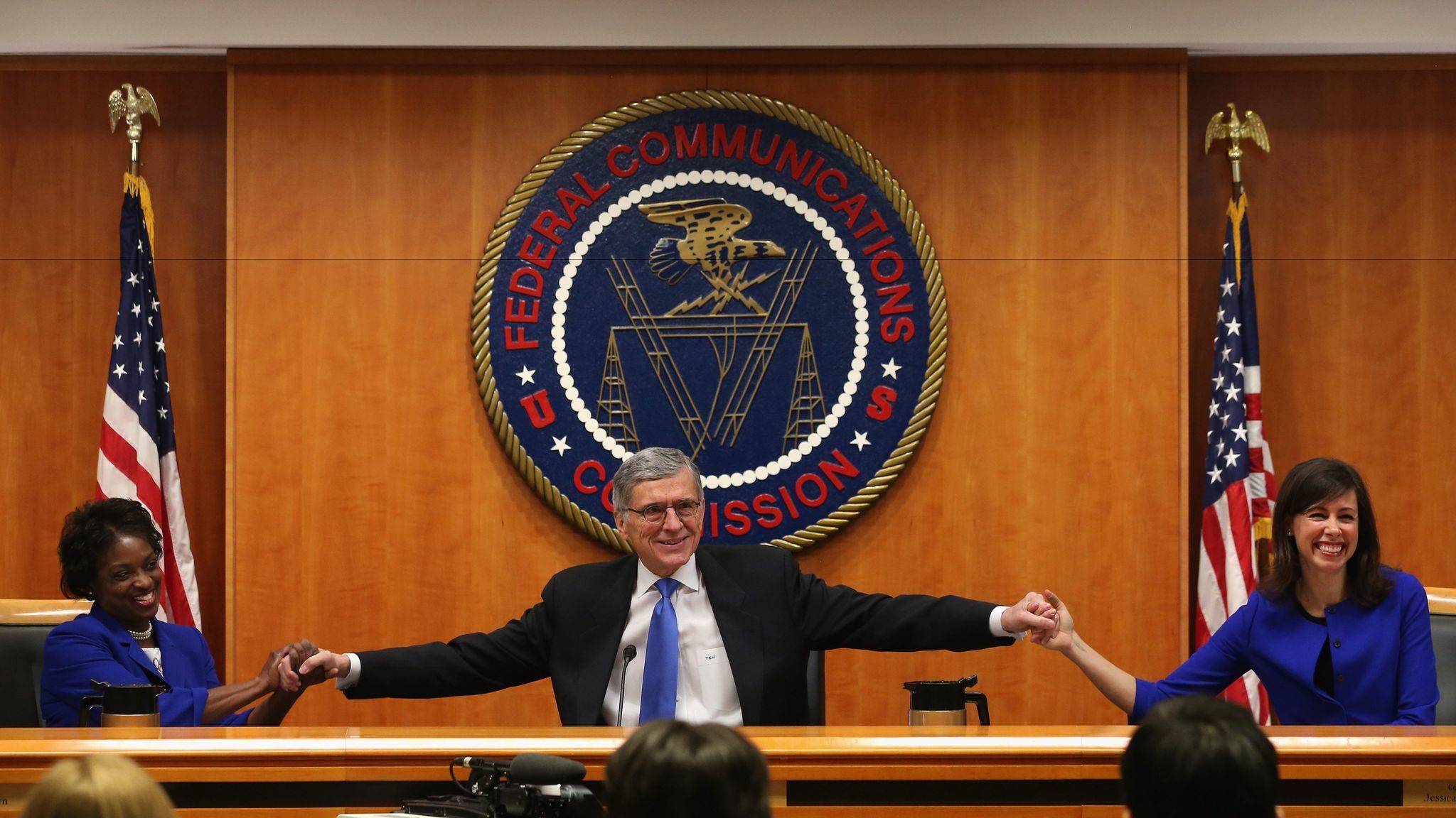 FCC Chairman Tom Wheeler, center, holds hands with fellow Democratic commissioners Mignon Clyburn, left, and Jessica Rosenworcel before the agency's vote on tough net neutrality rules on Feb. 26, 2015