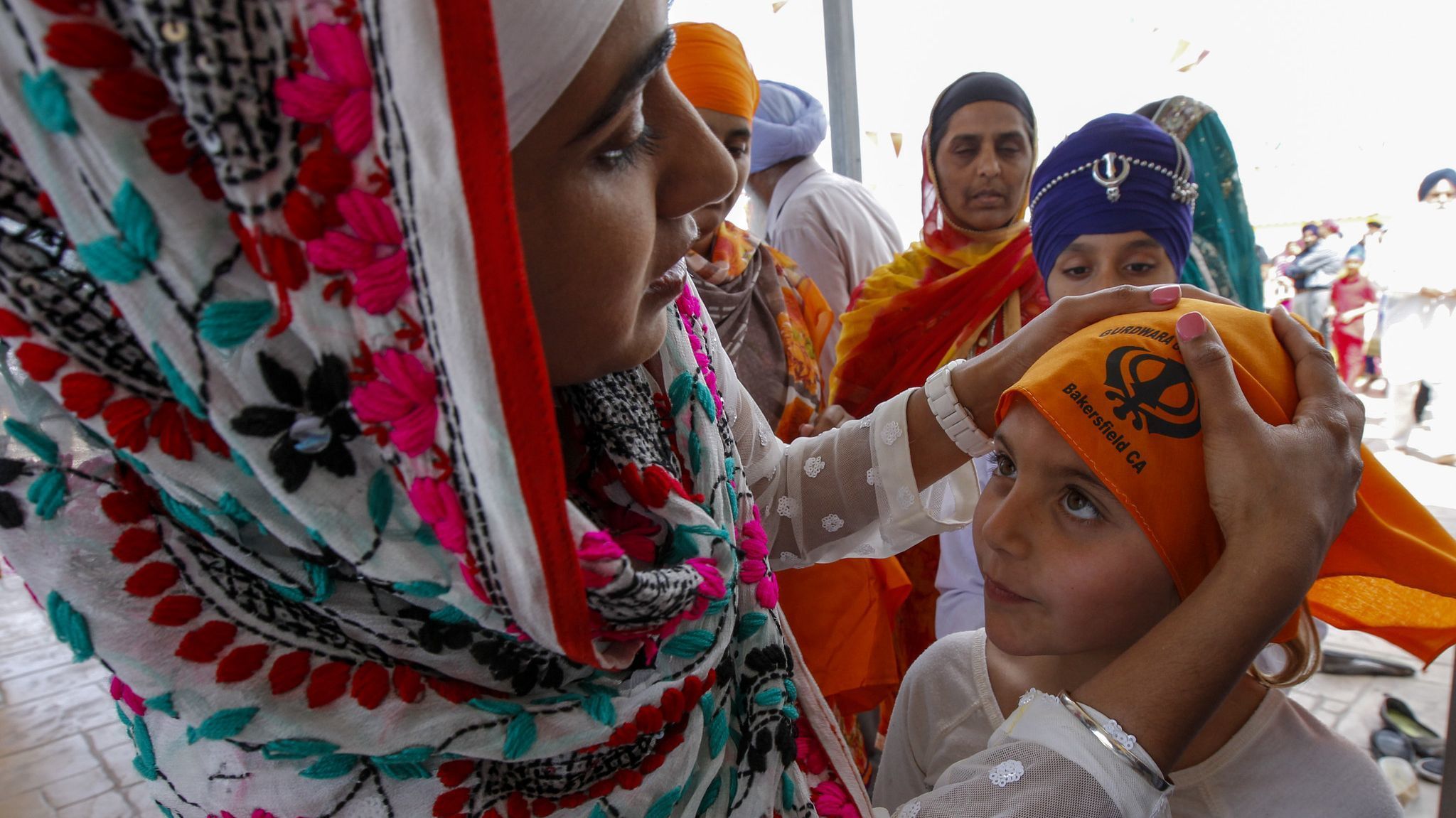 Sukhpreet "Sandy" Kaur, left, helps Emily Villarreal cover her head before entering the gurdwara.