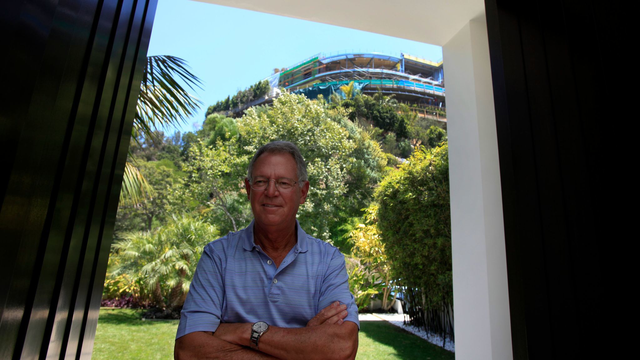 Joseph Horacek stands at the entrance to his Bel-Air home in 2014. Behind him, on the top of the hill, is the unfinished house on Strada Vecchia Road.