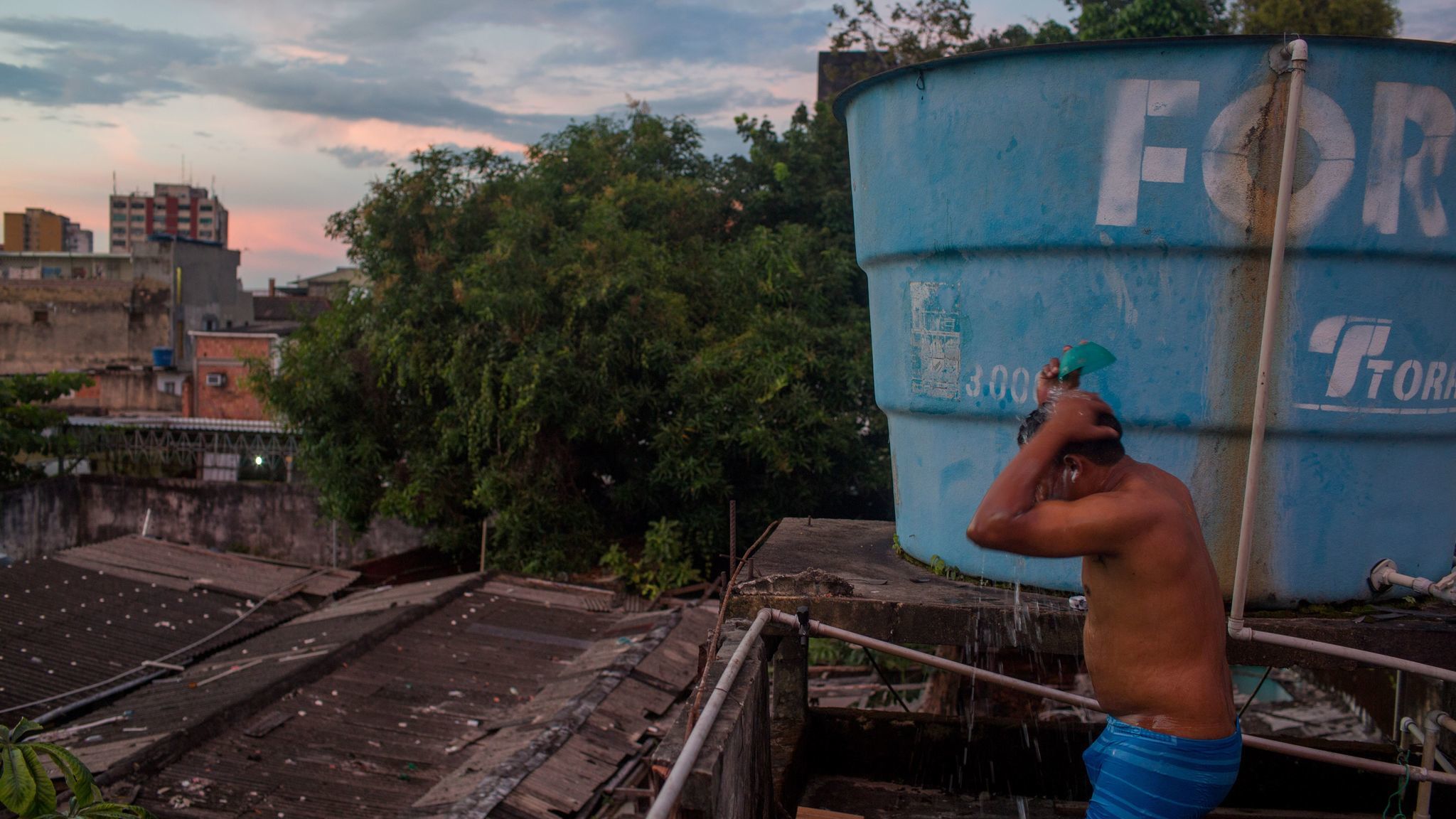 A Warao man bathes on a rooftop in Manaus, Brazil. About 350 Warao Indians live in public squares and old mansions in central Manaus.