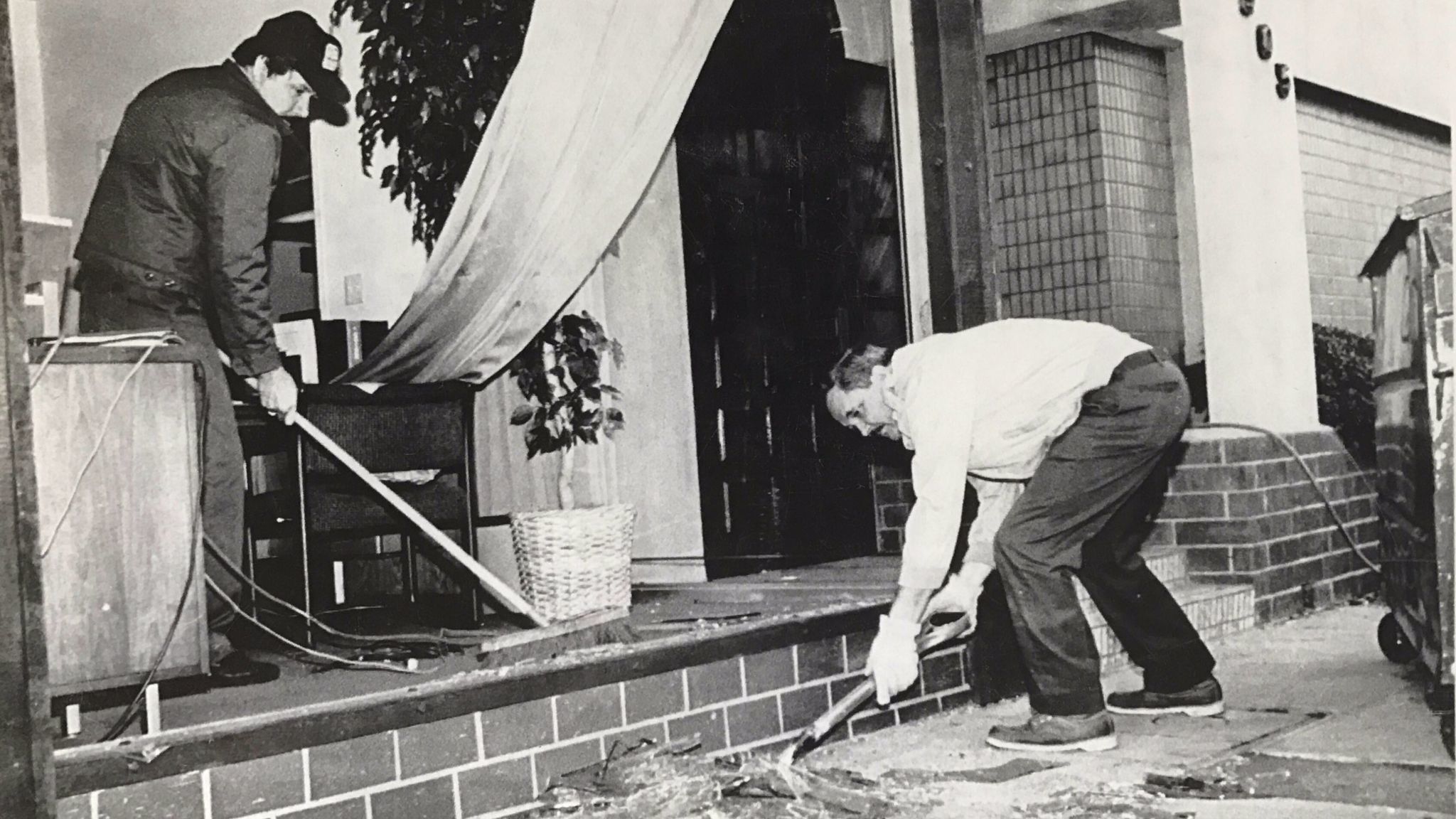Ronald Cloutier shovels plate glass as Javier Surrano sweeps glass from offices of Diversified Maintenance Services after a 5.0 earthquake hit south Pasadena in 1988.