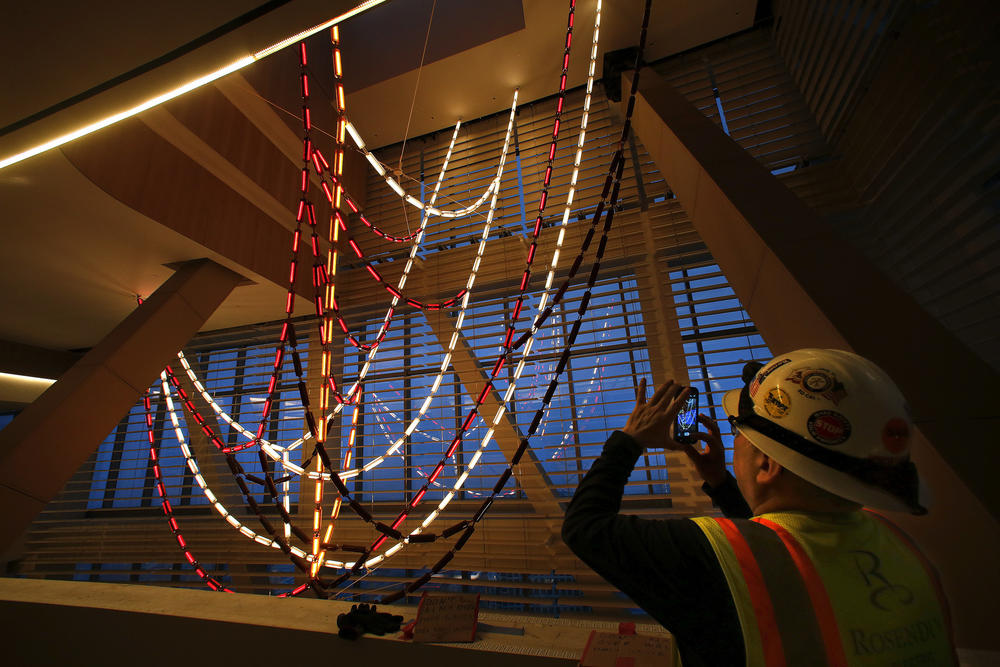 A construction worker photographs the three-story-high chandelier.