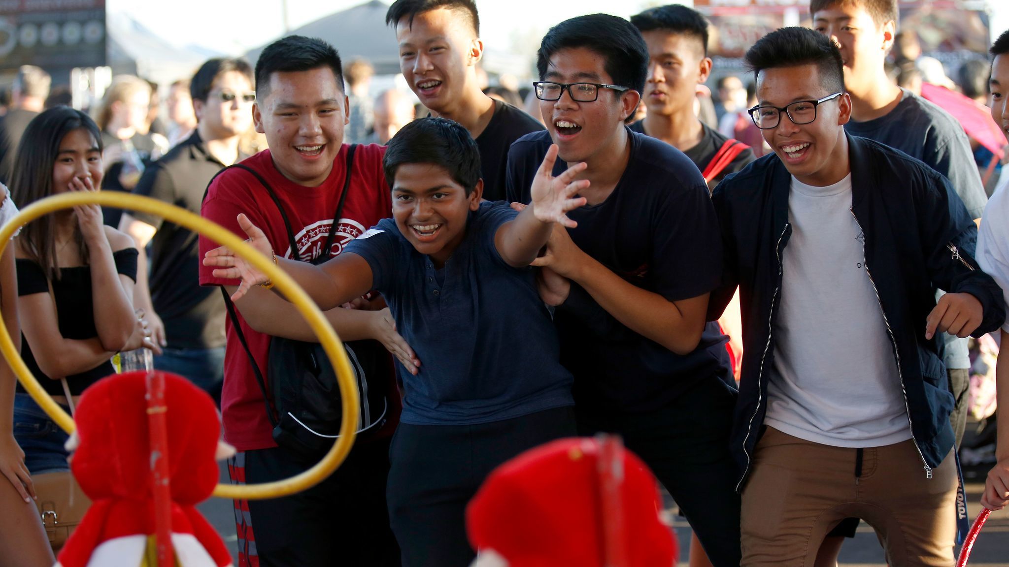 Roshan Kannan, 15, center, of Arcadia, is surrounded by friends as he tosses a ring in hopes of winning a stuffed animal at the 626 Night Market in Arcadia.