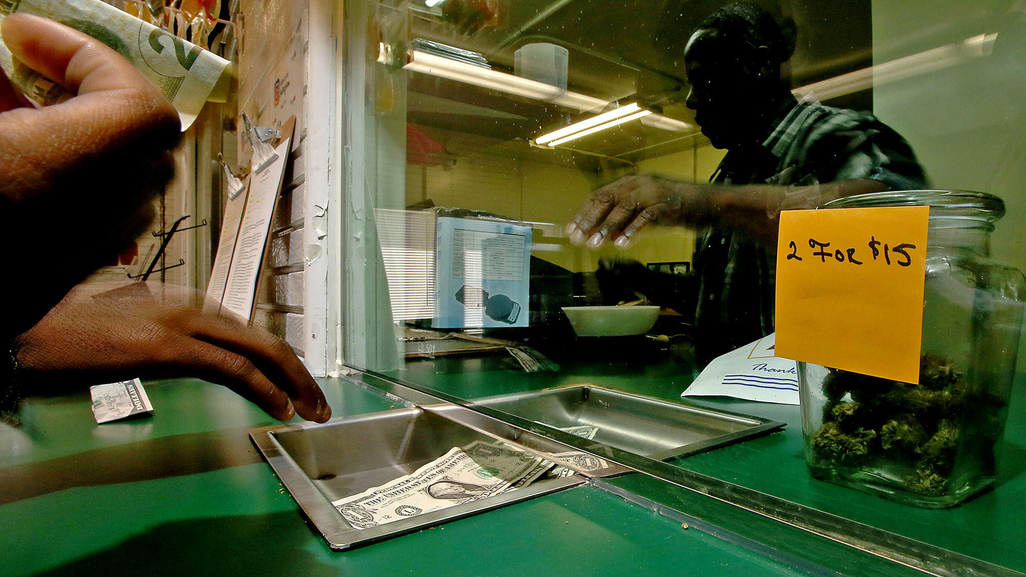 A medical marijuana patient pays for a purchase through a teller window at Medex, a dispensary on Century Boulevard in South Los Angeles.