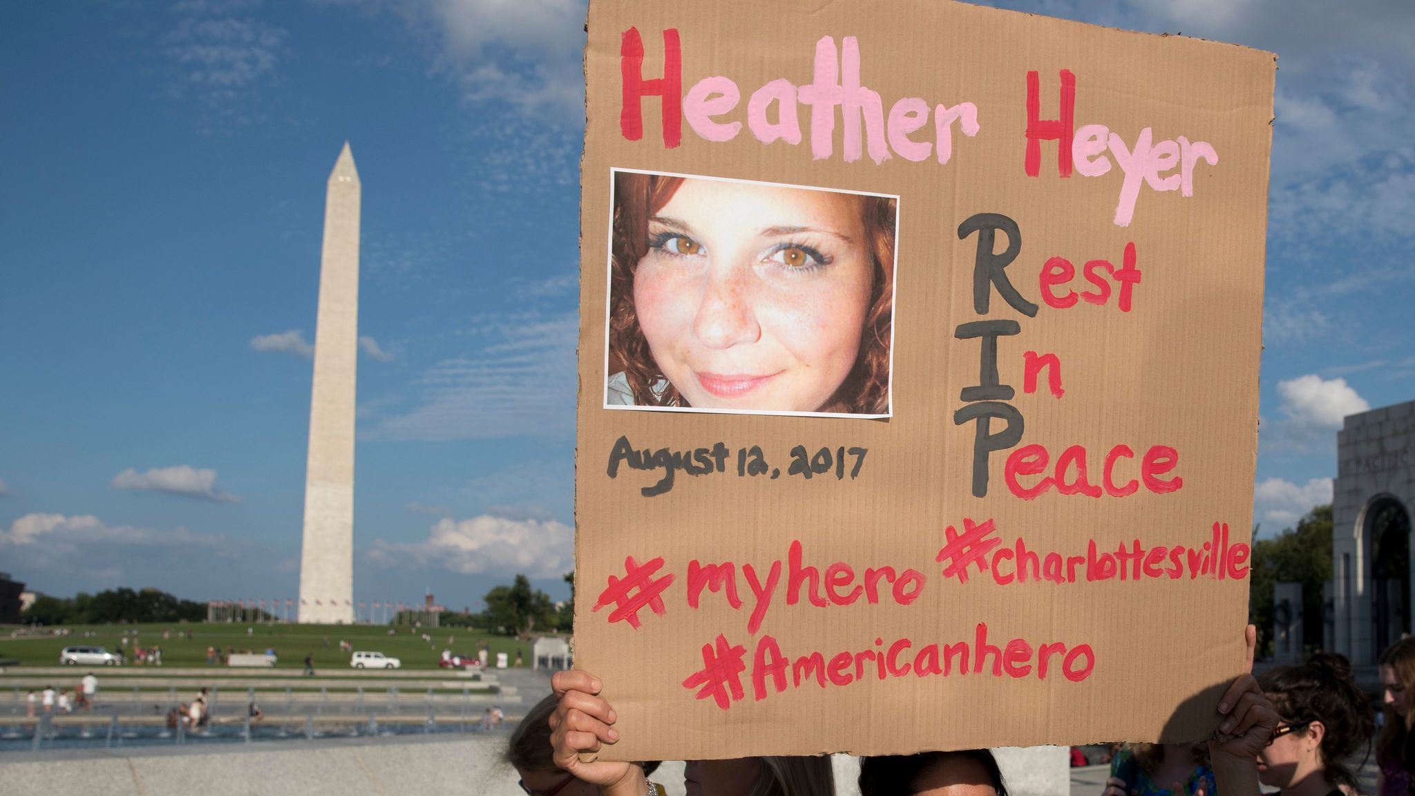 A woman holds a sign honoring Heather Heyer, a victim of this weekend's violence in Charlottesville, Va.,