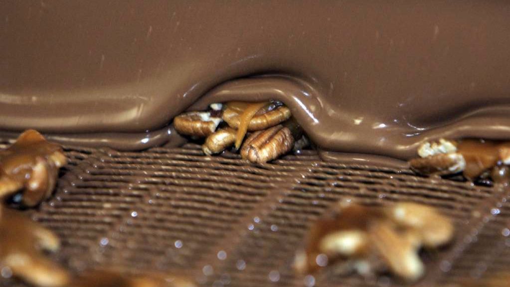 Pecans are draped with chocolate at the See's candy factory in Los Angeles.