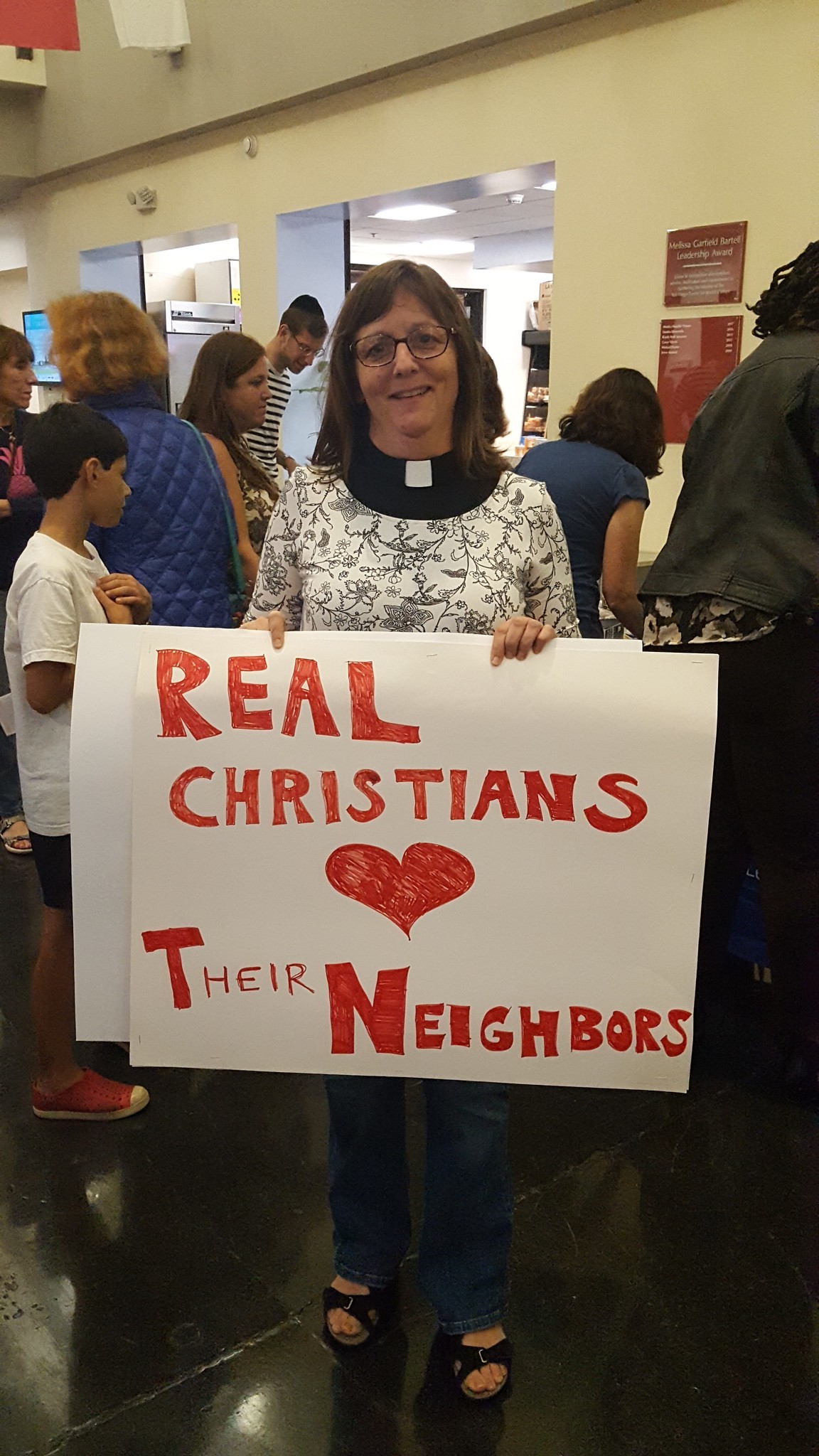 A Christian supporter with a sign that reads "Real Christians love their neighbors."