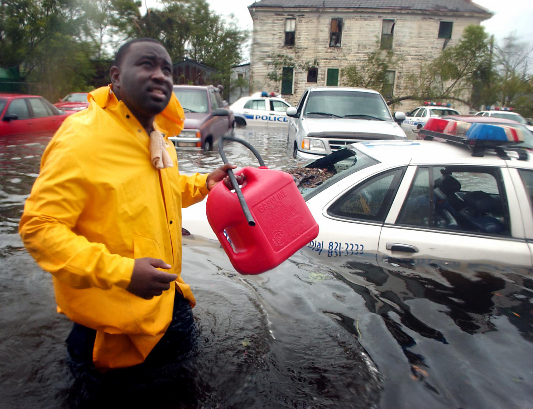 New Orleans Police Officer N. Daggs wades through the streets to siphon gas to fuel generators at Bywater Hospital, where many patients could not be safely moved.