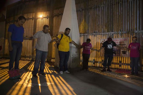 Activists pray at the wall between Mexico and the U.S. during a protest against the possibility of the deportation of Dreamers included in the DACA program. (Guillermo Arias / AFP/Getty Images)