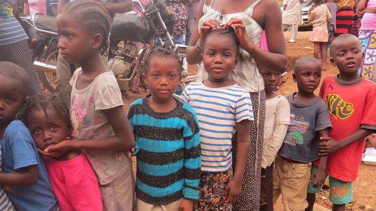 In this Aug. 19 photo, children displaced by floods and mudslides wait for food ration in Freetown,
