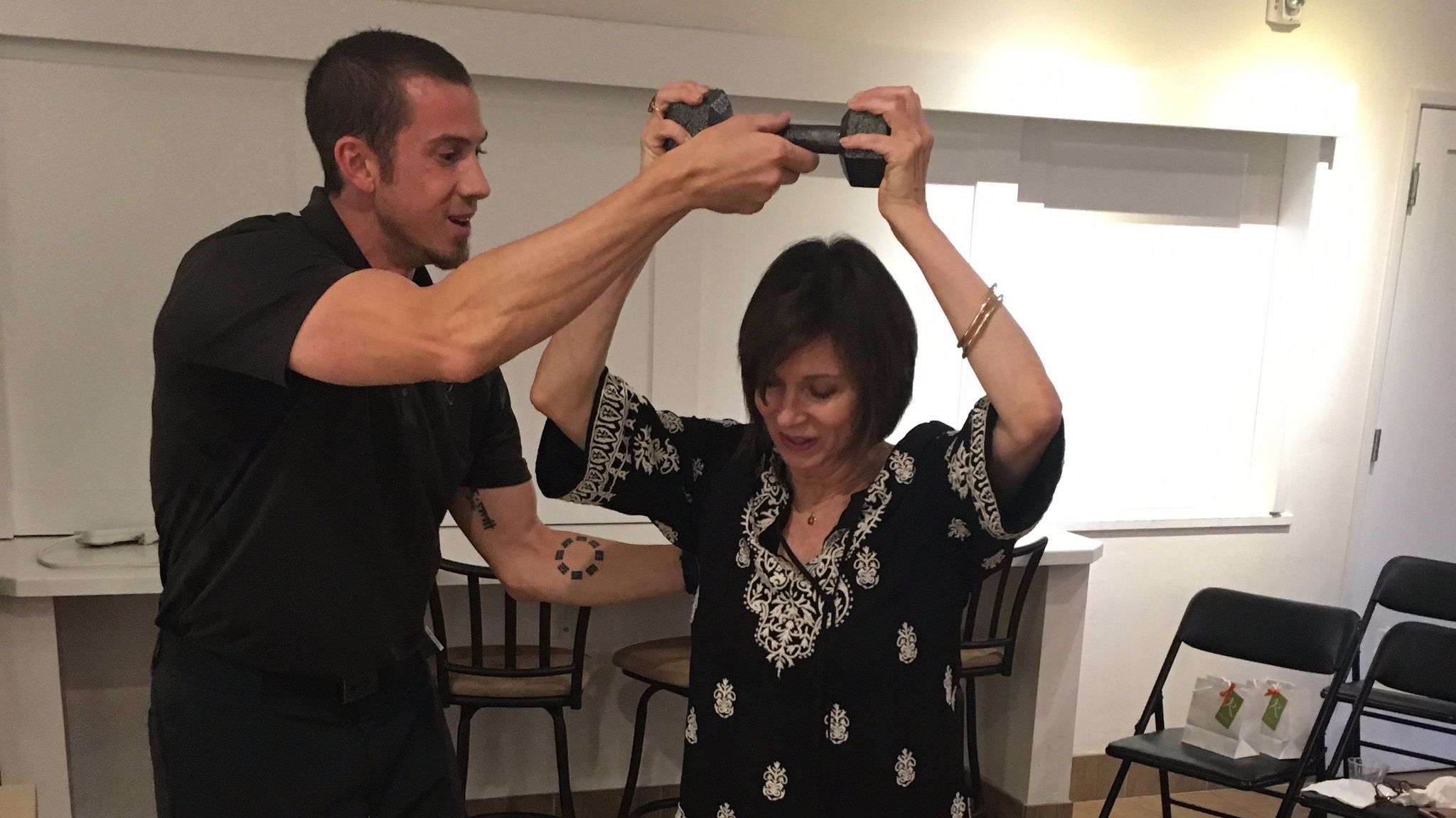 A Reneu Health staffer shows Mari Perez how to raise a weight for improved posture
