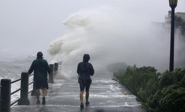 Pedestrians walk into huge waves crashing over the Battery park as Tropical Storm Irma hits Charleston, S.C., on Sept. 11, 2017. (Mic Smith / Associated Press)