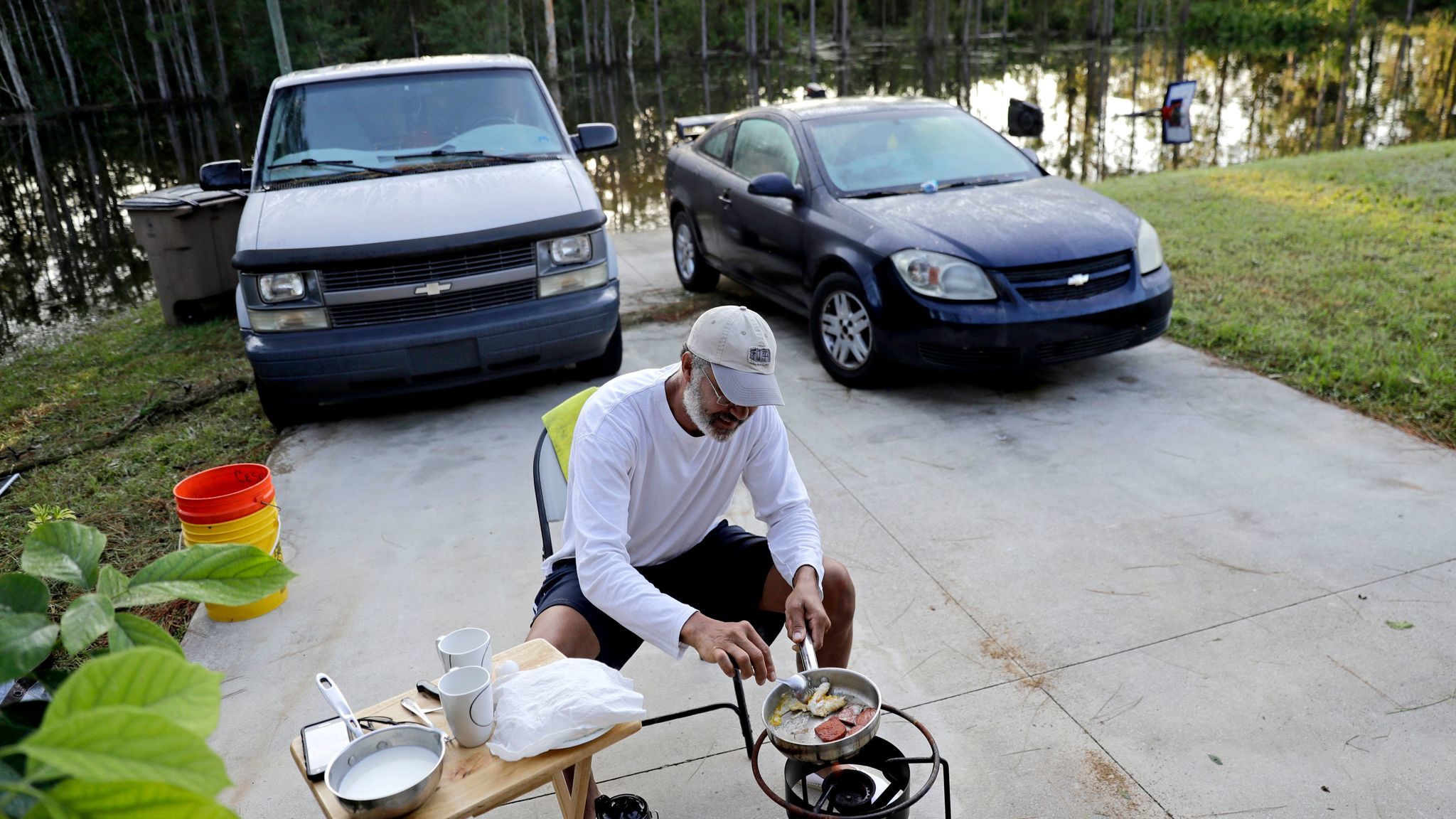 With his Fort Myers, Fla., neighborhood flooded, Cesar De La Cruz makes breakfast Sept. 12 on a propane stove in his driveway.